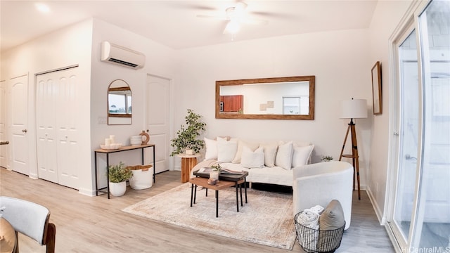 living room with light hardwood / wood-style floors, ceiling fan, and a wall mounted air conditioner