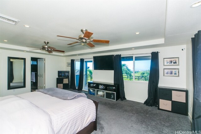 carpeted bedroom featuring a raised ceiling and ceiling fan