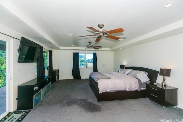 carpeted bedroom featuring ceiling fan, access to exterior, and a tray ceiling