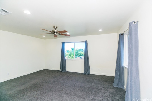 empty room with ceiling fan and dark carpet