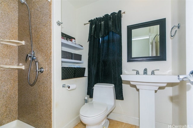 bathroom featuring tile patterned flooring, a tile shower, and toilet