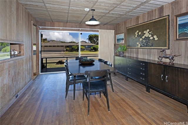 dining space with dark hardwood / wood-style floors and wood walls