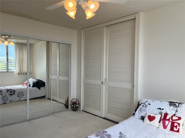 bedroom featuring ceiling fan, a textured ceiling, two closets, and carpet floors