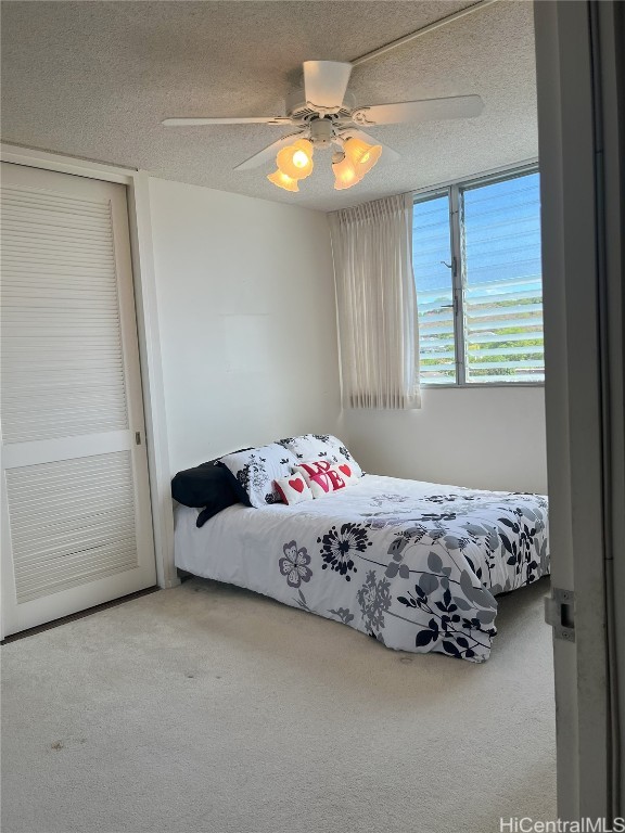 bedroom with a textured ceiling, carpet flooring, and ceiling fan