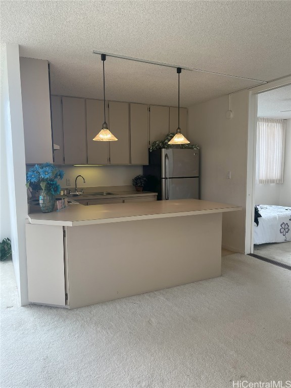 kitchen with stainless steel fridge, a textured ceiling, and decorative light fixtures