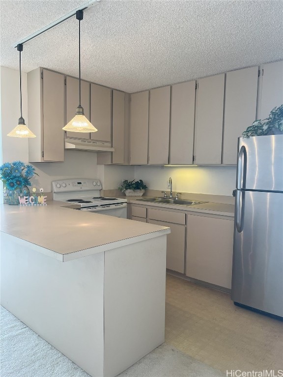 kitchen featuring sink, kitchen peninsula, decorative light fixtures, and stainless steel fridge