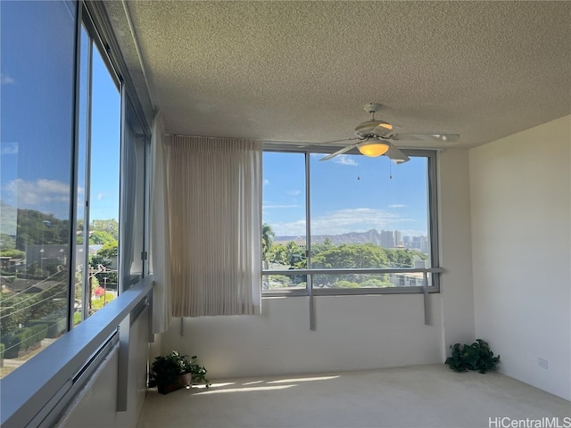 unfurnished room featuring a wealth of natural light, a textured ceiling, and ceiling fan