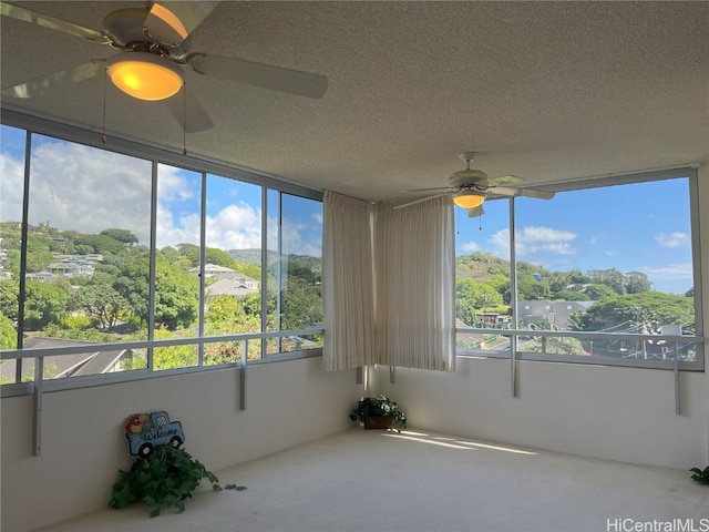 unfurnished sunroom with ceiling fan