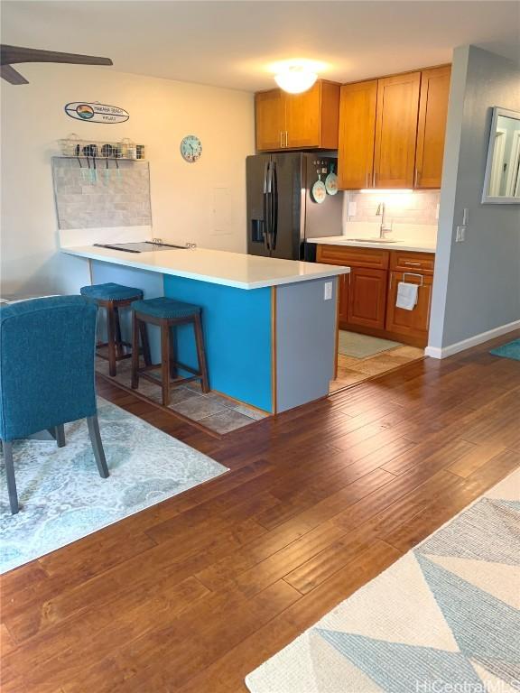 kitchen featuring backsplash, sink, black appliances, and hardwood / wood-style floors