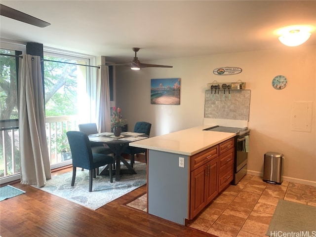 kitchen with stainless steel electric stove, kitchen peninsula, ceiling fan, and light wood-type flooring