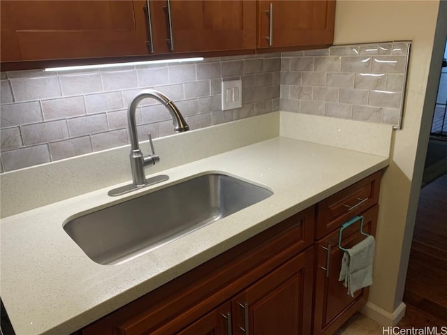 kitchen with tasteful backsplash, a sink, and light stone counters