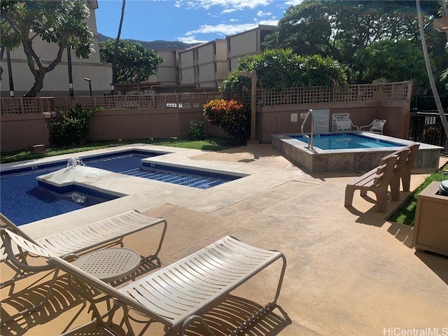 pool with a hot tub, fence, and a patio