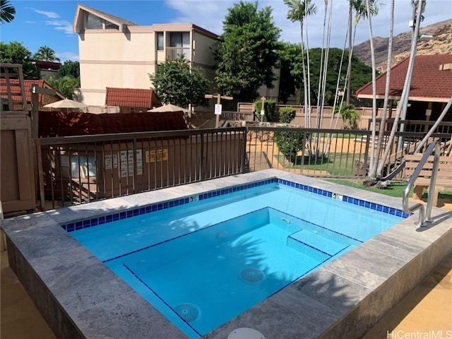 view of swimming pool with a mountain view, fence, and a community hot tub