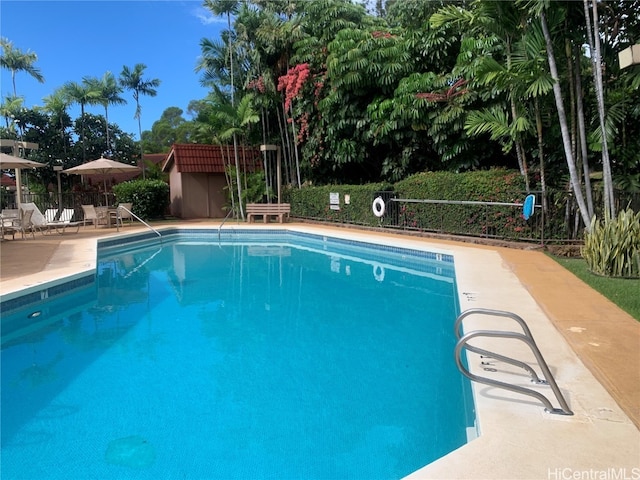 community pool with fence, an outbuilding, and a patio