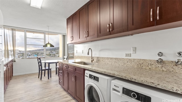 laundry area featuring sink, light hardwood / wood-style floors, a textured ceiling, and independent washer and dryer