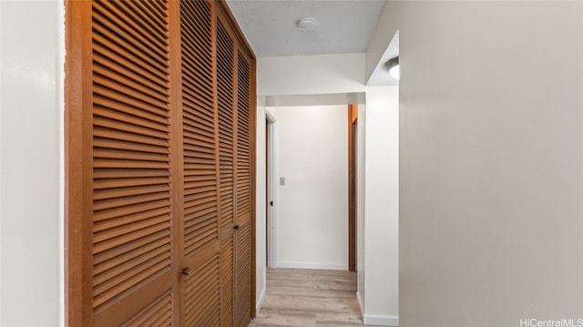 hallway featuring light hardwood / wood-style floors and a textured ceiling