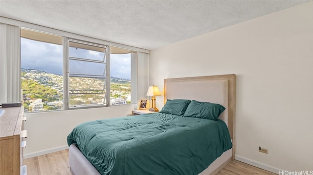 bedroom featuring a textured ceiling and light hardwood / wood-style flooring