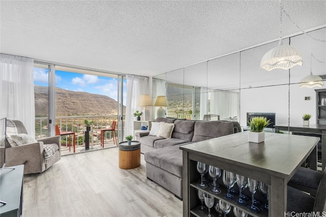 living room featuring a mountain view, a wall of windows, wood-type flooring, and a textured ceiling