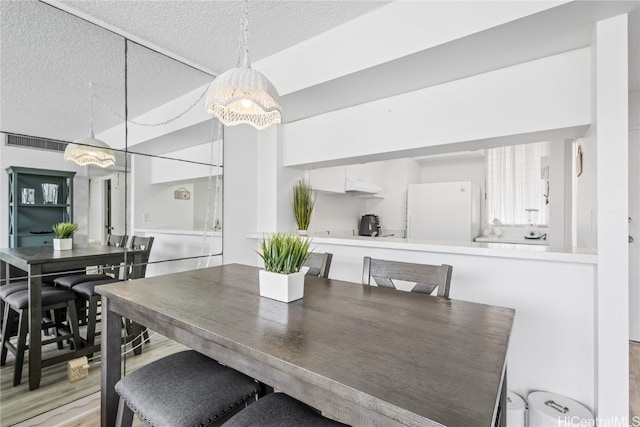 dining area with light wood-type flooring and a textured ceiling