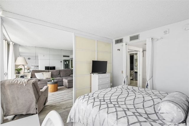 bedroom with light hardwood / wood-style floors and a textured ceiling