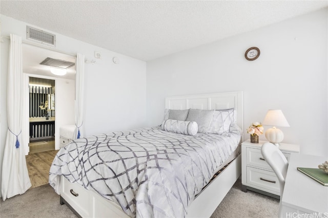 bedroom with light colored carpet and a textured ceiling