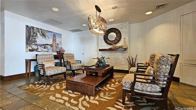 sitting room featuring visible vents, baseboards, and stone tile flooring