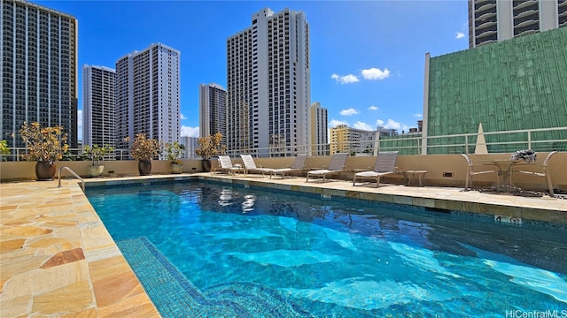 pool with a view of city, a patio area, and fence