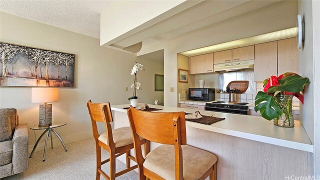 kitchen featuring black appliances, cream cabinets, and a textured ceiling