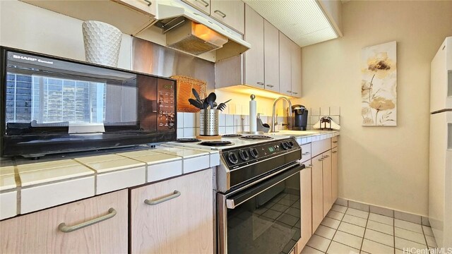 kitchen with tile countertops, black appliances, sink, and light tile patterned floors