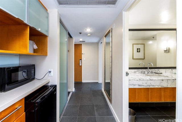 hall with dark tile patterned floors and sink