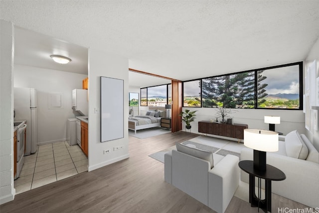 living room featuring washer / dryer, a textured ceiling, and light hardwood / wood-style floors