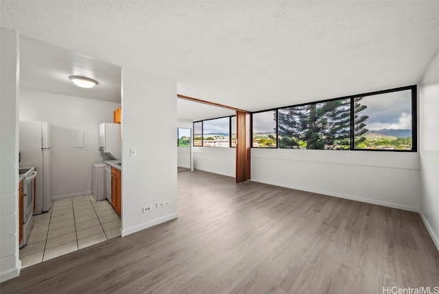 interior space with light wood-type flooring, a textured ceiling, and white appliances