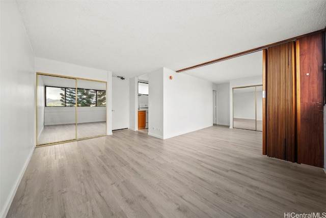 spare room featuring light hardwood / wood-style floors and a textured ceiling