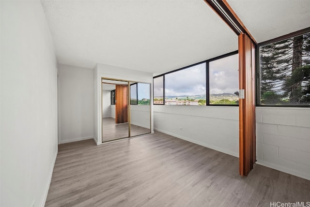 unfurnished bedroom featuring a textured ceiling, light hardwood / wood-style flooring, and a closet