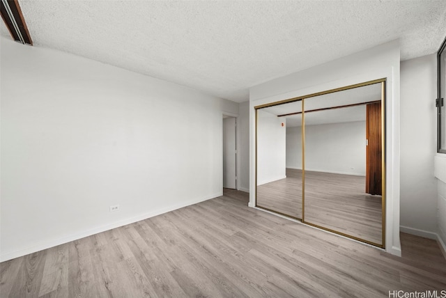 unfurnished bedroom featuring a closet, a textured ceiling, and light wood-type flooring