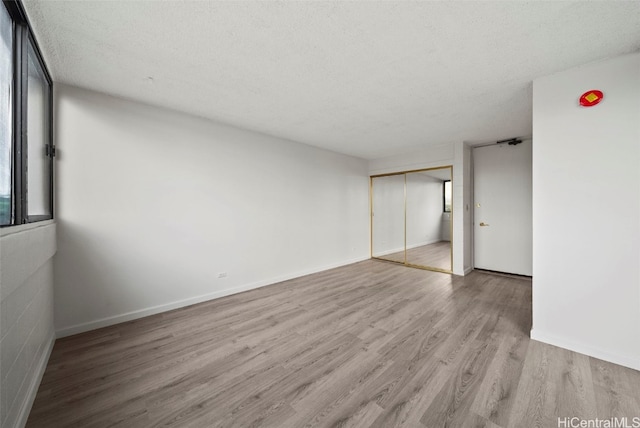 empty room featuring a textured ceiling and light hardwood / wood-style floors