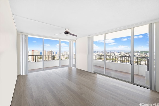 unfurnished room with wood-type flooring, floor to ceiling windows, and ceiling fan