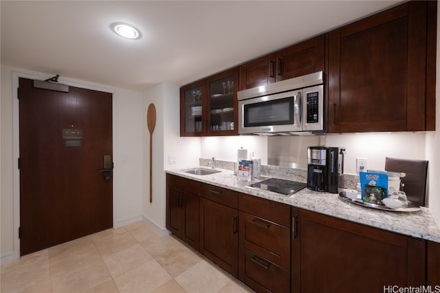 kitchen with light stone countertops, dark brown cabinets, and sink