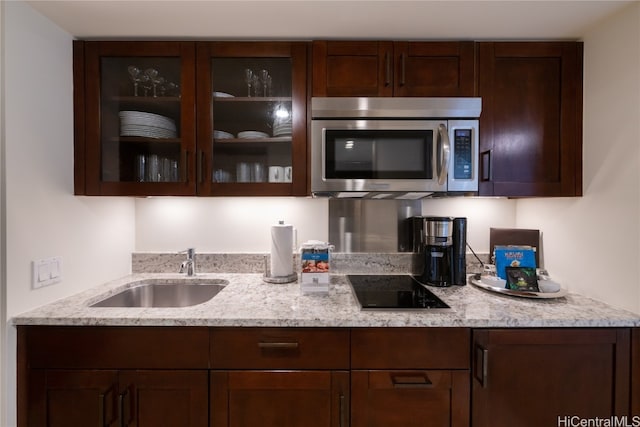 kitchen featuring black electric cooktop, light stone countertops, sink, and dark brown cabinetry