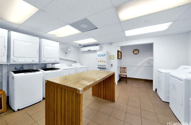 laundry area with a wall mounted air conditioner, washer and clothes dryer, stacked washer and clothes dryer, and light tile patterned flooring