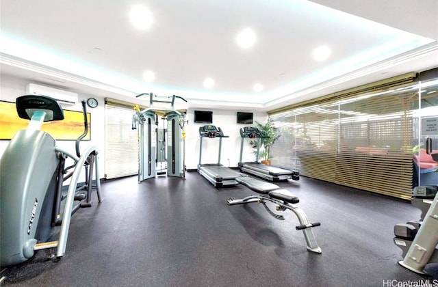 workout area featuring a healthy amount of sunlight, an AC wall unit, and a tray ceiling