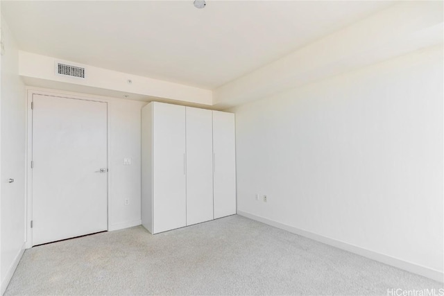 unfurnished bedroom featuring light carpet and a closet