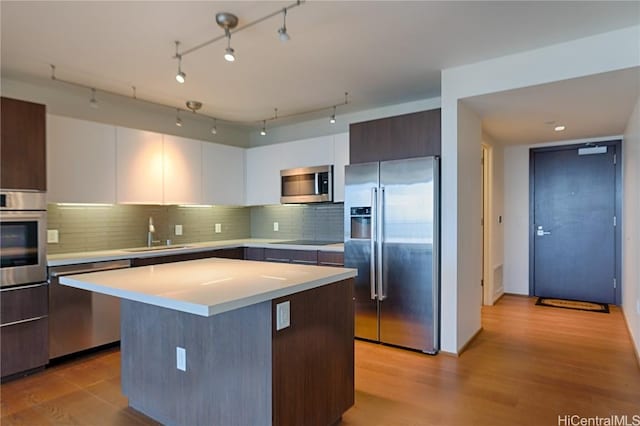 kitchen featuring a kitchen island, appliances with stainless steel finishes, white cabinetry, sink, and dark brown cabinets