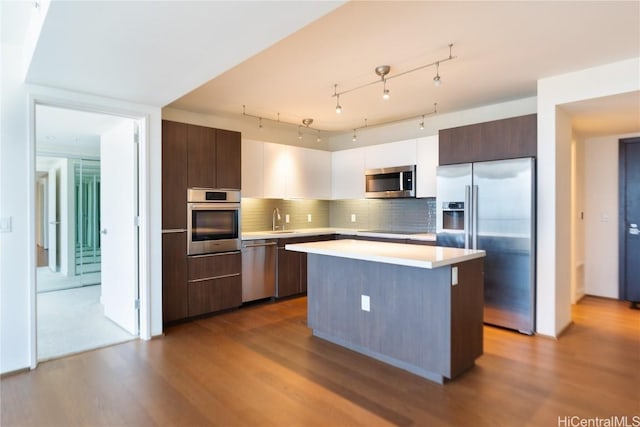 kitchen featuring stainless steel appliances, a center island, dark brown cabinets, and backsplash