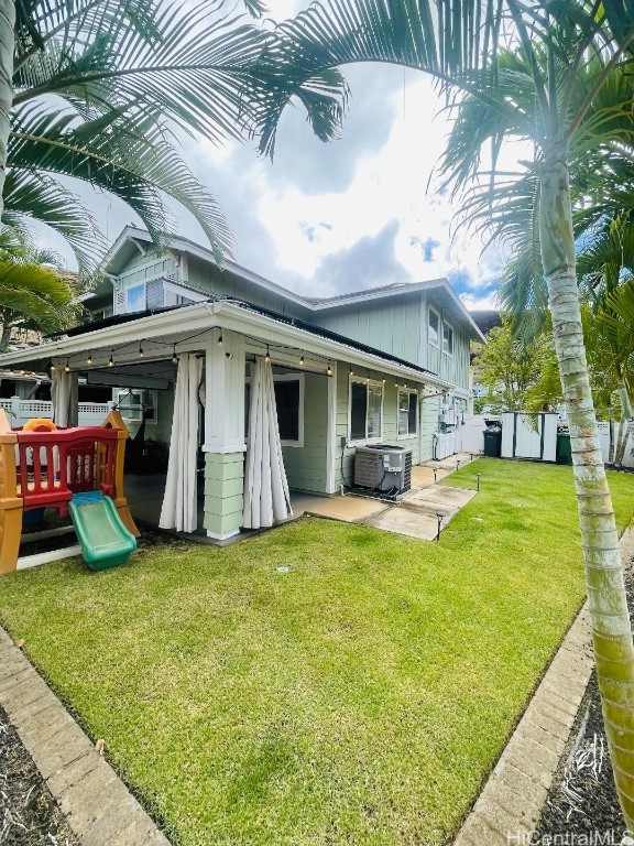 back of house with a patio area, central AC, a lawn, and a playground