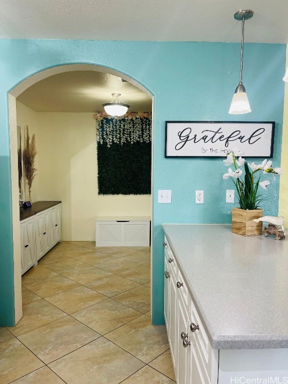 kitchen with white cabinets, light tile patterned floors, and decorative light fixtures