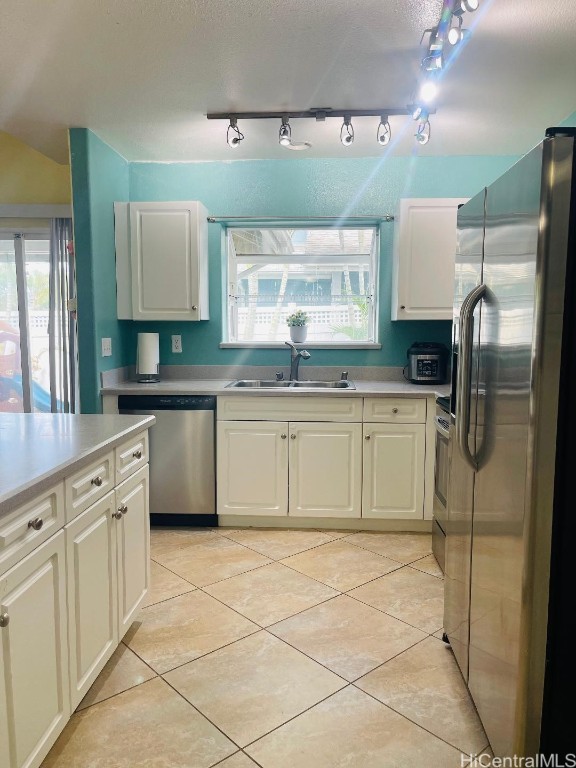 kitchen featuring light tile patterned flooring, white cabinetry, appliances with stainless steel finishes, sink, and rail lighting