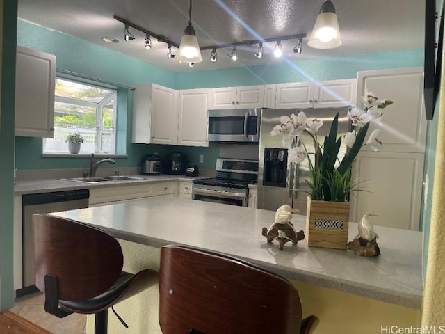 kitchen featuring white cabinetry, appliances with stainless steel finishes, sink, and decorative light fixtures