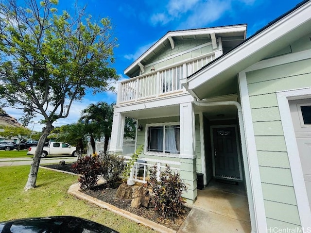 view of side of home featuring a lawn and a balcony