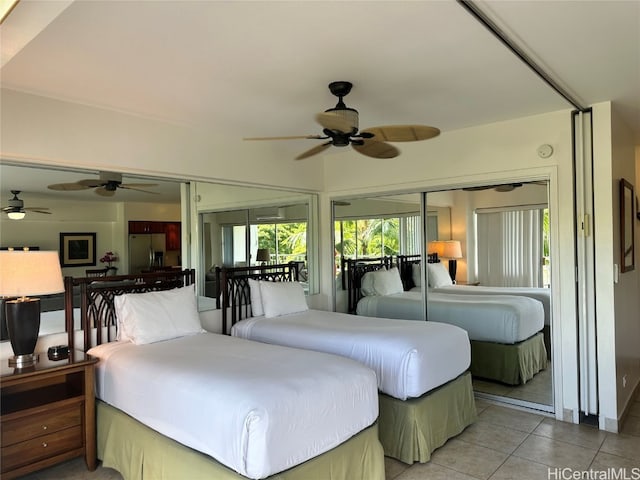 bedroom featuring stainless steel refrigerator with ice dispenser, ceiling fan, a closet, and light tile patterned floors